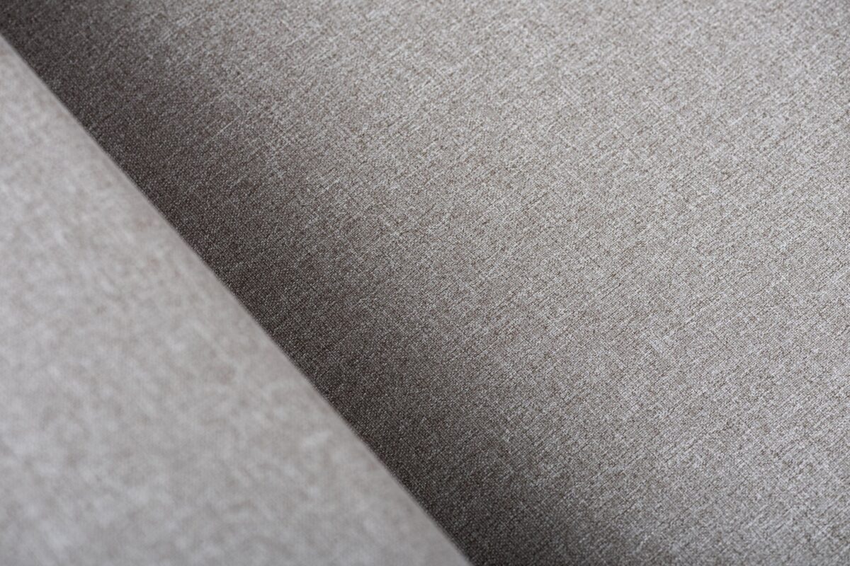 Close-up van een grijze stof met textuur, diagonale lijnen en zachte belichting. De weefstructuur en fijne details van de stof zijn goed te zien.