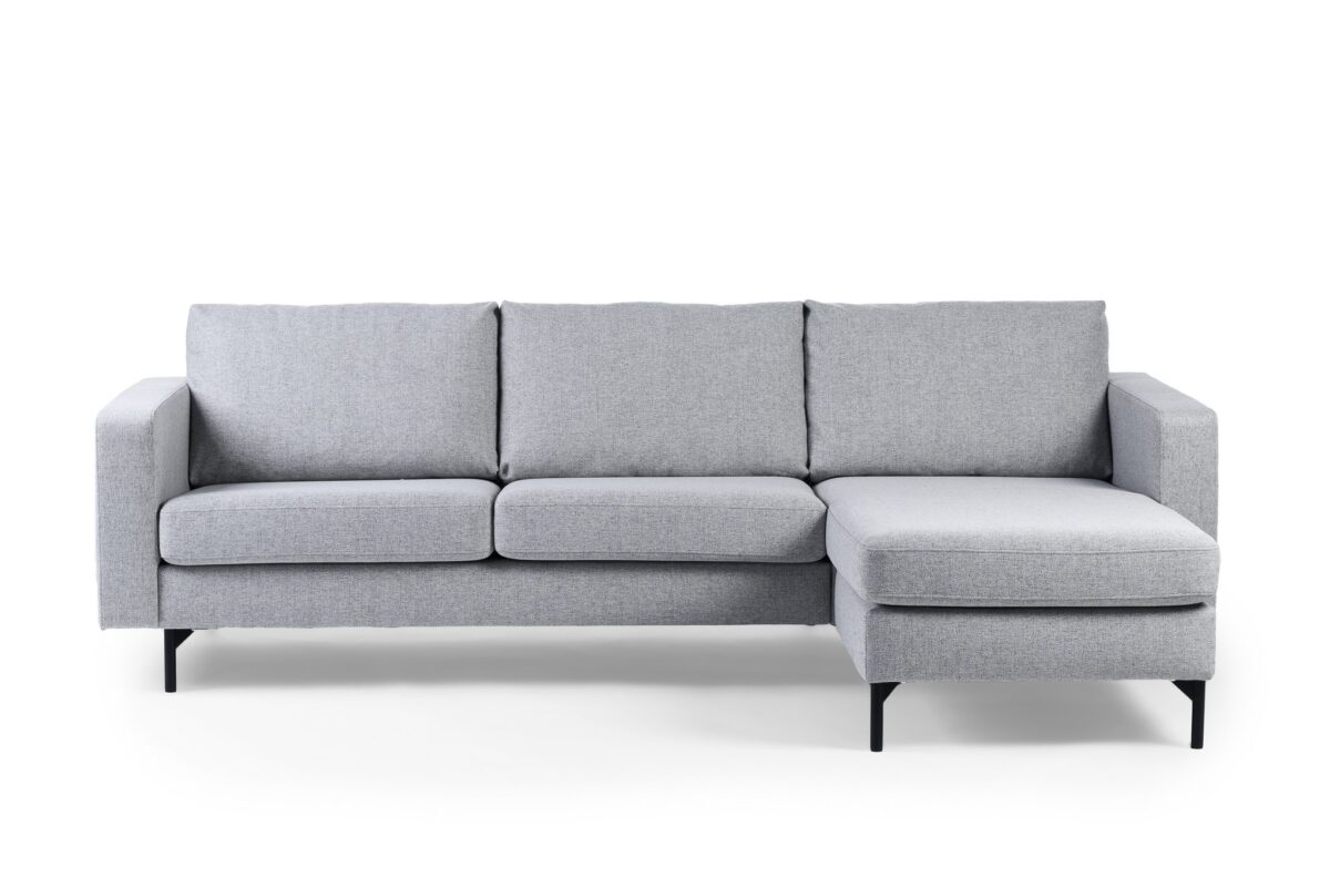 De 3 zits bank CL L+R, bekleed met stof Chloe in C311 grijs, is een moderne grijze hoekbank met drie zitkussens, een rechter chaise longue en slanke zwarte metalen poten, getoond tegen een witte achtergrond.