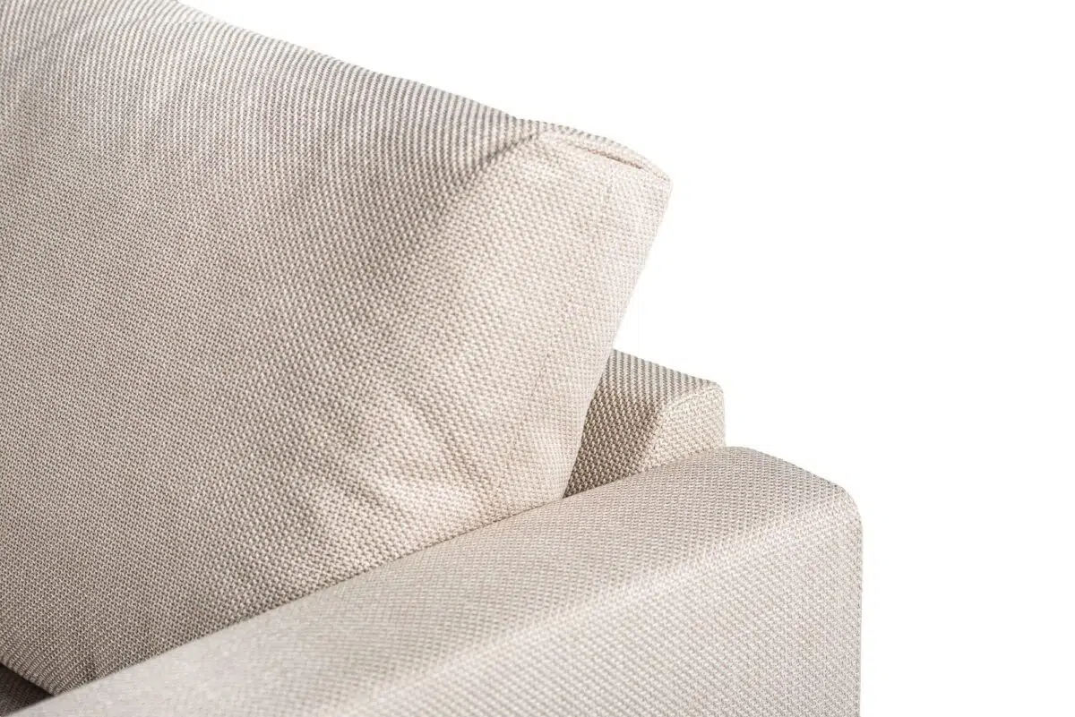 Close-up van de bovenste hoek van de 3 zits hoek links sofa in Bjorn 24 W460 beige stof, met gestructureerde bekleding, een gecapitonneerde rugleuning en een deel van de armleuning tegen een effen witte achtergrond.