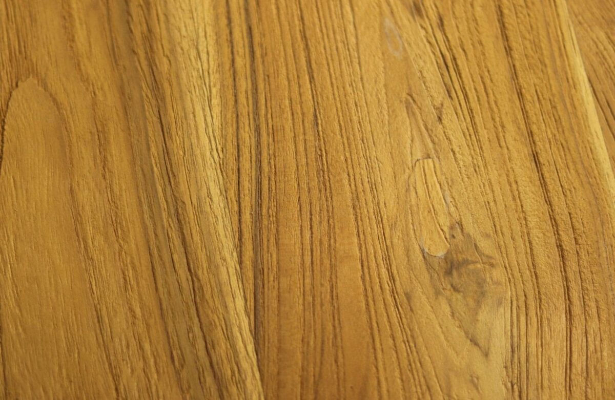 Close-up van een houten oppervlak met een natuurlijk, gestructureerd nerfpatroon. Het hout heeft lichte tot middelbruine tinten met zichtbare knopen en subtiele variaties in kleur en textuur, wat de organische uitstraling benadrukt.