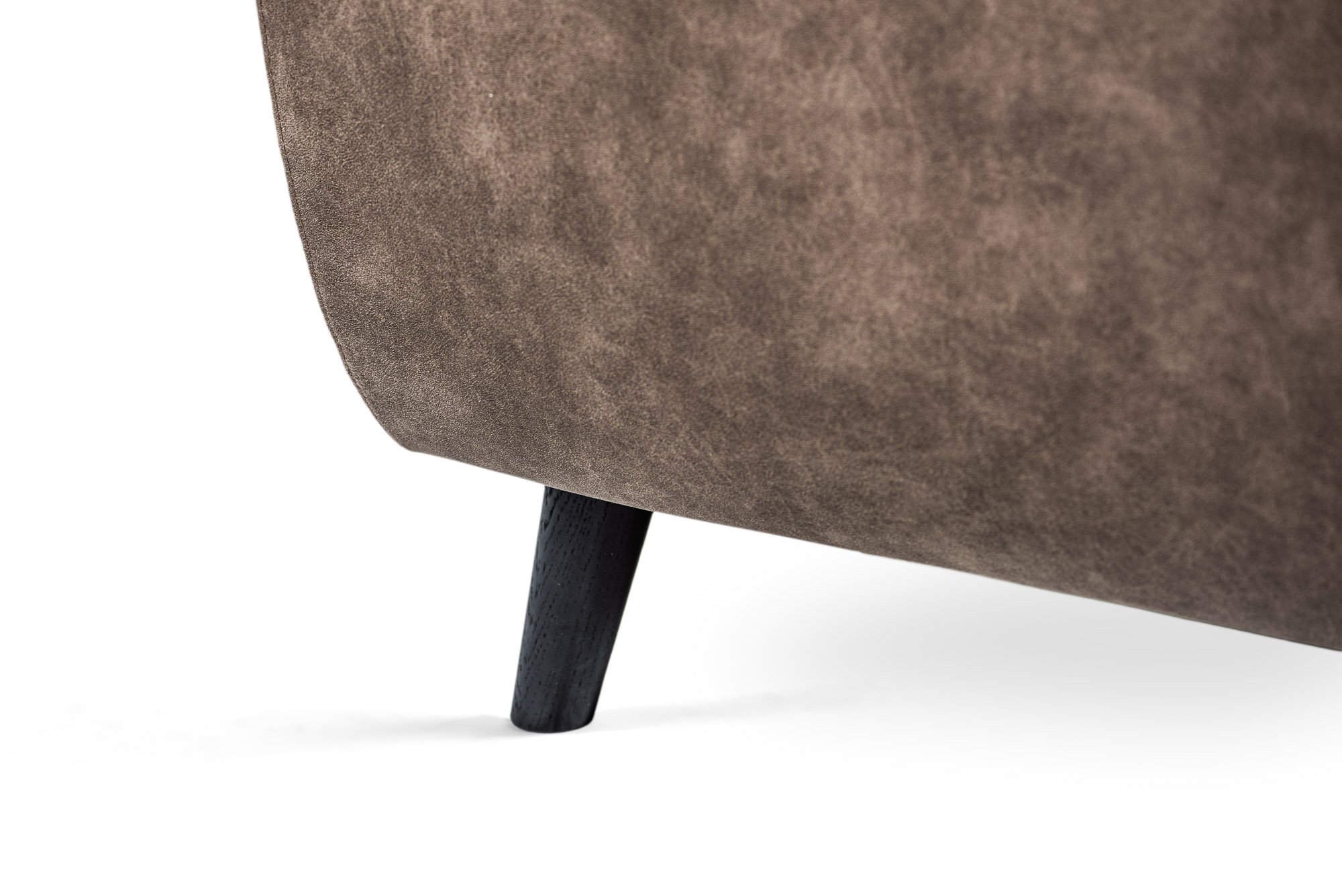 Close-up van een bruine stoffen bankpoot met een strakke zwarte houten poot, tegen een witte achtergrond.