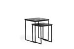 Twee in elkaar passende vierkante tafels met zwarte metalen frames en donkere getextureerde tafelbladen. De grotere tafel is iets hoger en beide hebben een minimalistisch design, tegen een witte achtergrond.