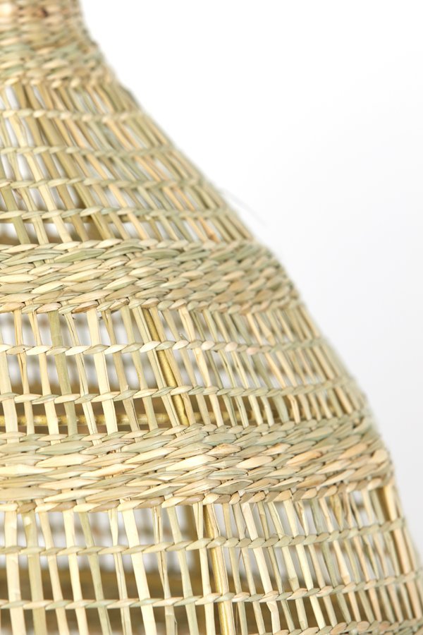 Close-up van een gevlochten rieten mand met de nadruk op de ingewikkelde patronen en textuur. De natuurlijke vezels creëren een herhalend geometrisch ontwerp, wat het vakmanschap van de mand benadrukt tegen een effen witte achtergrond.