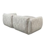 Twee beige ottomans met een geometrisch patroon in lichtgrijs. Ze zijn naast elkaar geplaatst en tonen een pluche, gestoffeerde textuur en modern design. De ottomans hebben rechthoekige vormen met licht afgeronde randen.