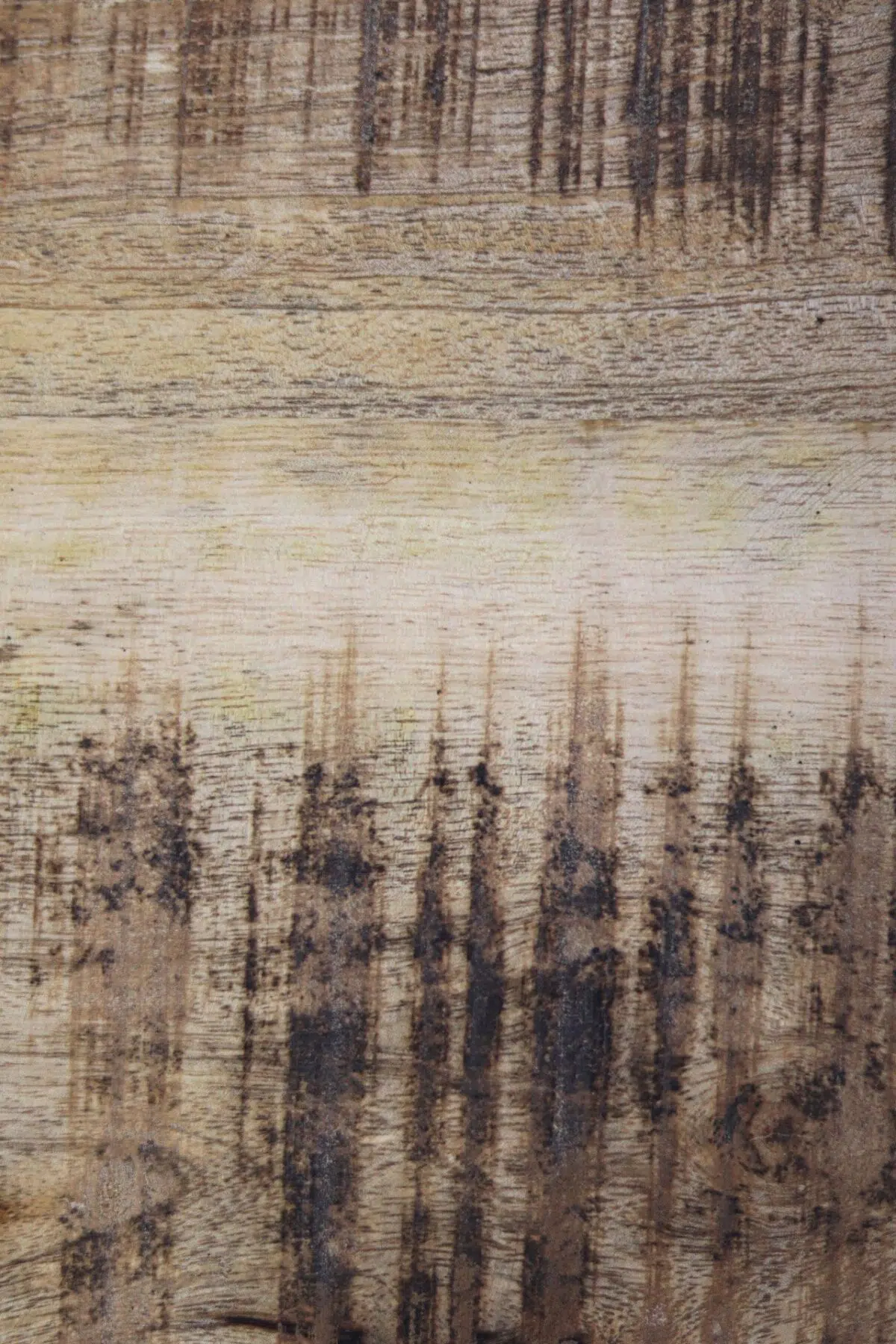 Close-up van verweerd hout met duidelijke verticale donkere strepen en nerfpatronen. Het hout heeft een vervaagde, versleten uitstraling, met een mix van lichte en donkerbruine tinten, wat een rustieke textuur creëert.