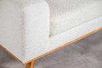 Close-up van een moderne witte stoffen bank met houten poten op een lichtgrijze vloer. Het ontwerp benadrukt strakke lijnen en minimale esthetiek.