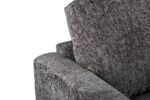 Close-up van een moderne, getextureerde grijze stoffen fauteuil met een focus op de armleuning en rugleuning. De stof heeft een subtiel geweven uiterlijk, wat de stoel een stijlvolle en eigentijdse uitstraling geeft.