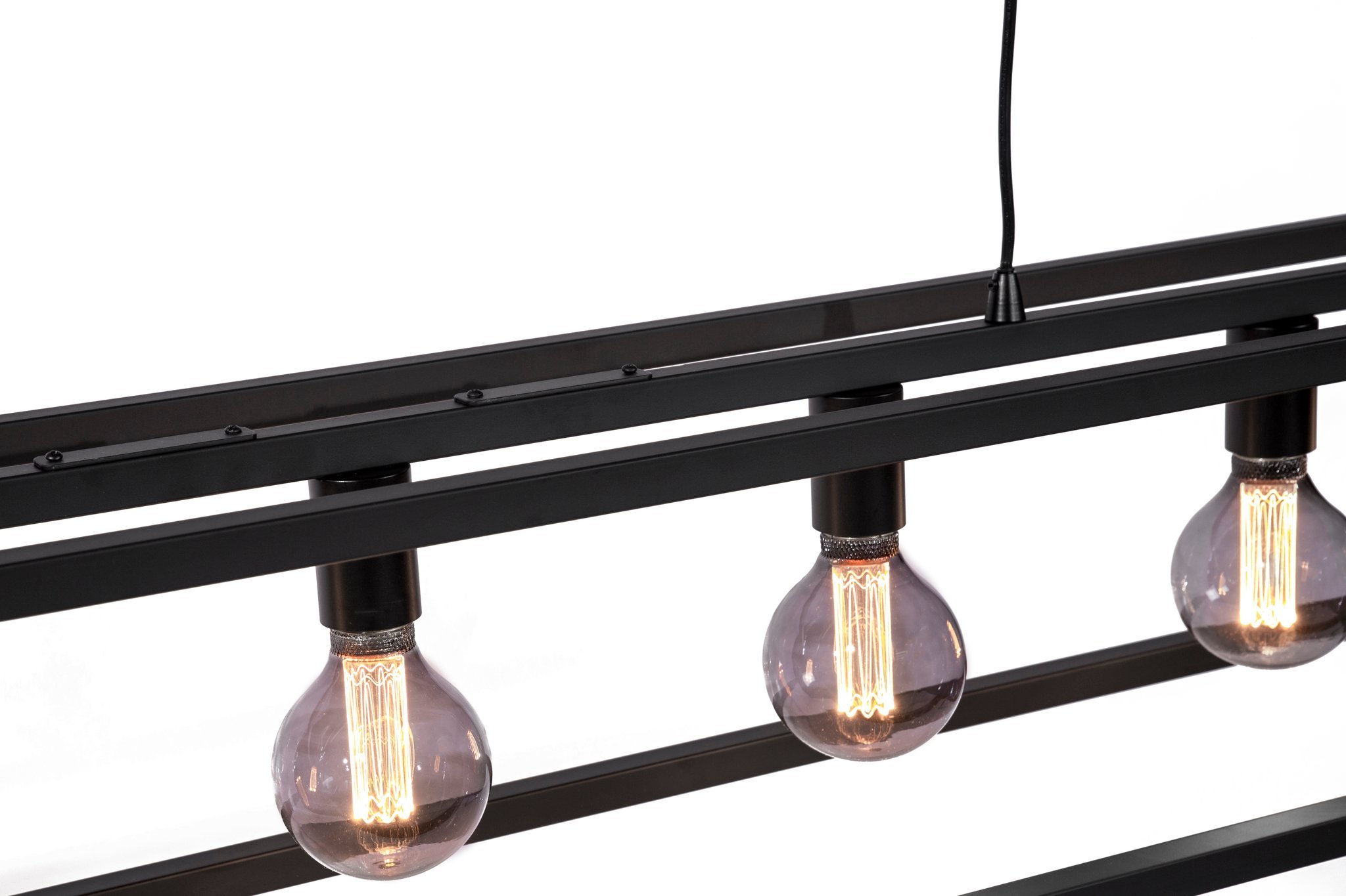 Close-up van een moderne lamp met drie zichtbare Edison-lampen gemonteerd op een strak zwart metalen frame. De lamp heeft een minimalistisch ontwerp en een zichtbaar zwart snoer loopt van bovenaf. De achtergrond is effen wit.