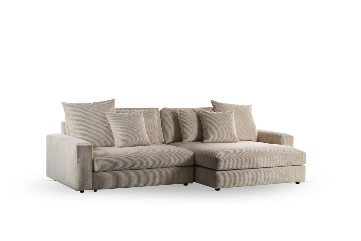 Een ruime 3-zits sofa, model CL L+R in Lincoln 83 stof (RIB920 naturel), heeft pluche kussens en een chaise lounge aan de rechterkant, tegen een effen witte achtergrond.