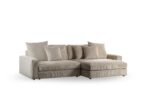 Een ruime 3-zits sofa, model CL L+R in Lincoln 83 stof (RIB920 naturel), heeft pluche kussens en een chaise lounge aan de rechterkant, tegen een effen witte achtergrond.