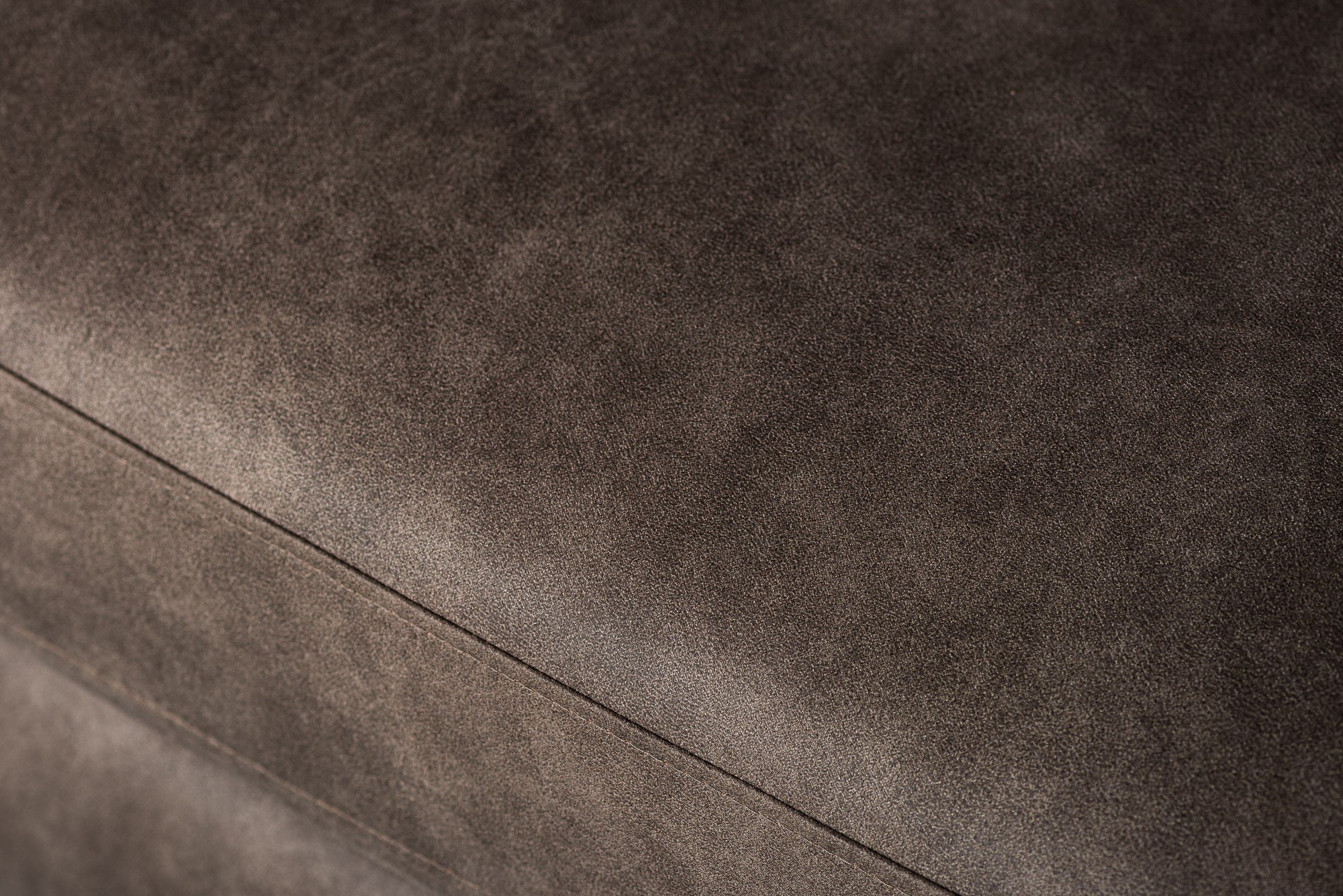 Close-up van de gestructureerde taupe stof (stof Yuma 34) met subtiele nuances en stiksels op de bekleding van de S520 3 zits hoek links bank.