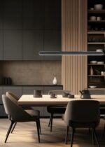 Een moderne keuken met donkere kasten en open houten planken. Een houten eettafel is omringd door vier donkere stoelen. Verschillende schalen en een theepot staan op de tafel. Een strakke hanglamp hangt erboven en verlicht de ruimte zachtjes.
