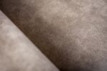 Close-up van de 3 zits bank CL L+R bekleed met de stof Savannah S520 taupe. De gladde suède textuur, subtiele kleurvariaties en fijne nerf benadrukken het pluche, fluweelachtige oppervlak.