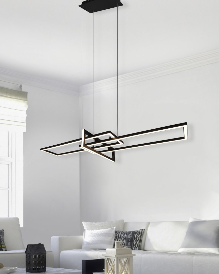 Een moderne woonkamer heeft een geometrische hanglamp die aan het plafond hangt. De kamer heeft een witte bank met decoratieve kussens, een vierkante houten salontafel met een kaarslantaarn erop en een groot raam met witte jaloezieën.