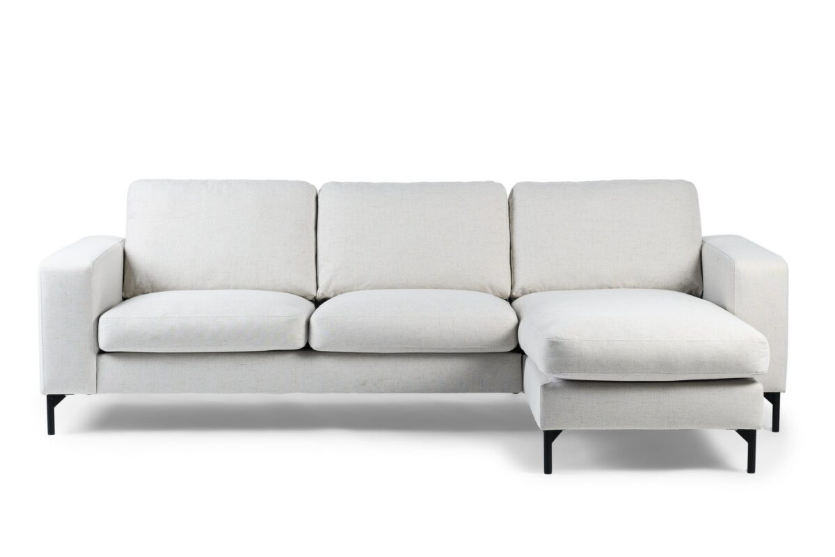 Een moderne 3-zitsbank, CL L+R model, bekleed met Valente V920 naturel stof, met een chaise lounge en slanke zwarte metalen poten.