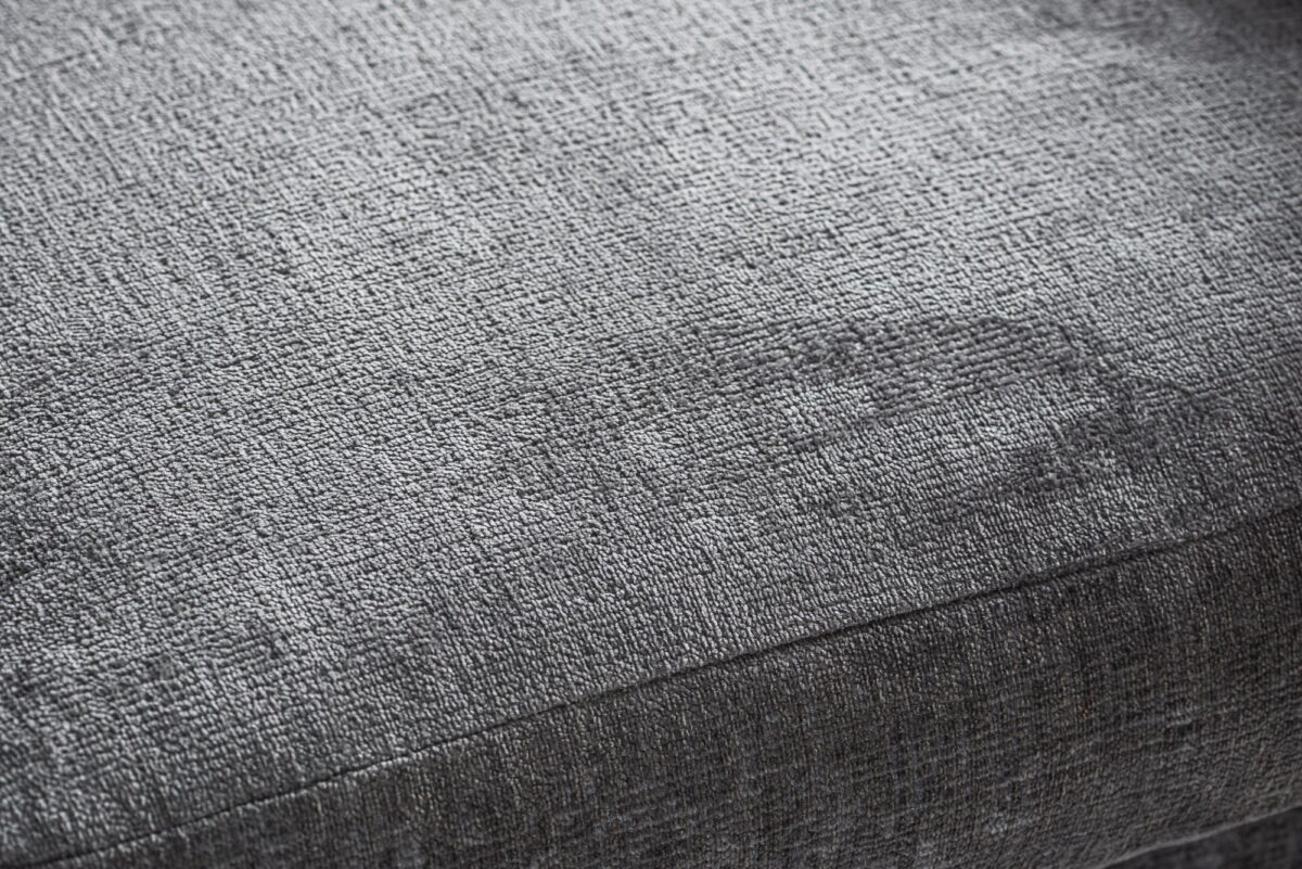 Close-up van de 3 zits hoeklinks in stof Perfect Harmony 82, R311 grijs, met de nadruk op de geweven stof met textuur en subtiele grijze schaduw voor een zachte, comfortabele look.