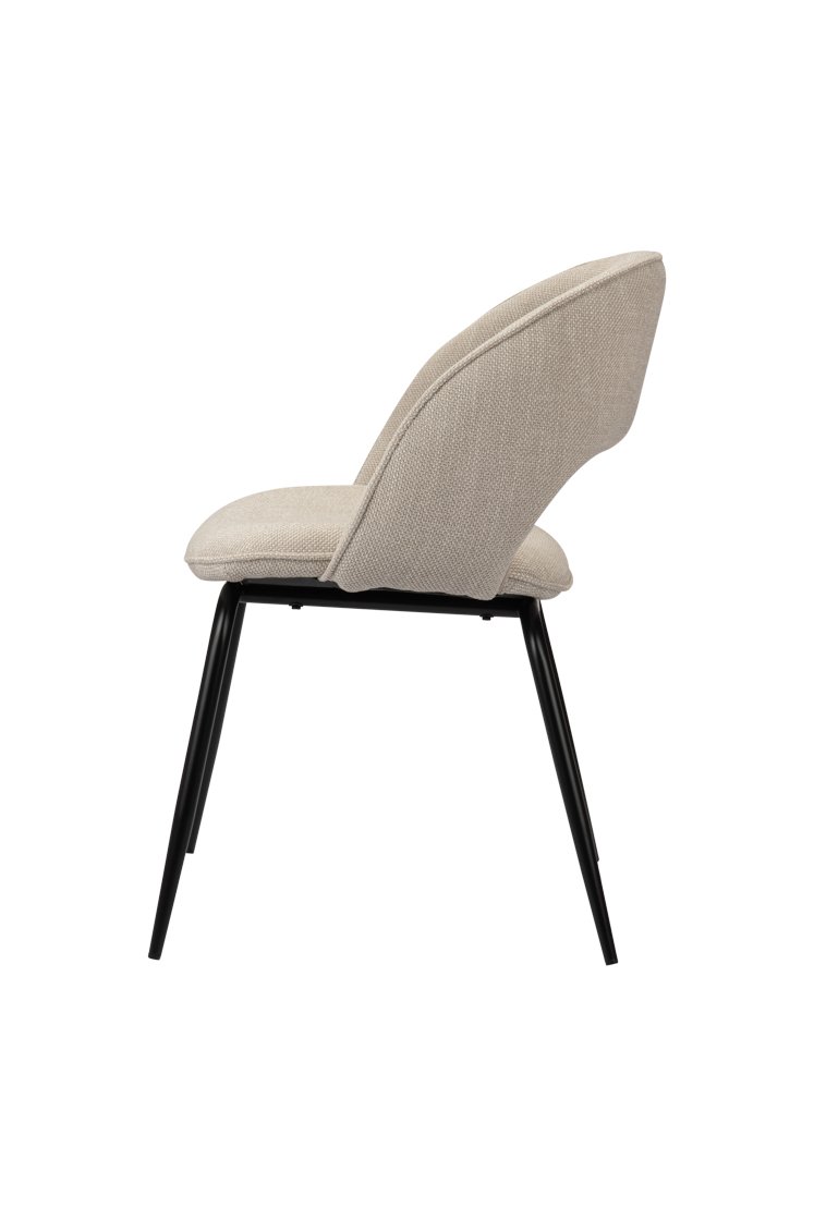 Zijaanzicht van een moderne stoel met een beige stoffen zitting en rugleuning, ondersteund door strakke zwarte metalen poten. Het ontwerp is minimalistisch en eigentijds, waarbij de ergonomische vorm van de stoel wordt benadrukt.