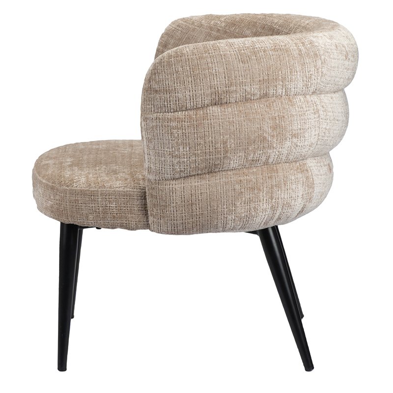 Een moderne stoel met een lichtbruine, gestructureerde stof en een ronde, gewatteerde rugleuning. Hij heeft vier strakke zwarte metalen poten en een eigentijds design. De stoel is van de zijkant bekeken.