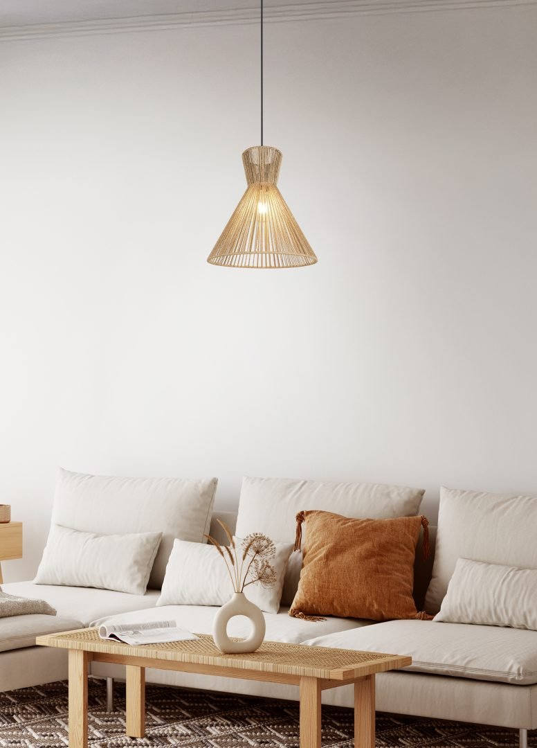 Een minimalistische woonkamer met een witte bank en bruin kussen, een houten salontafel en een geweven hanglamp. Een kleine vaas met gedroogde bloemen staat op de tafel. De kamer heeft een neutraal kleurenpalet en een patroonkleed.