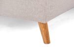 Close-up van een beige stoffen hoekbank met een enkele houten poot op een witte achtergrond. De stof heeft een subtiel structuurpatroon en de houten poot is taps toelopend en lichtbruin.