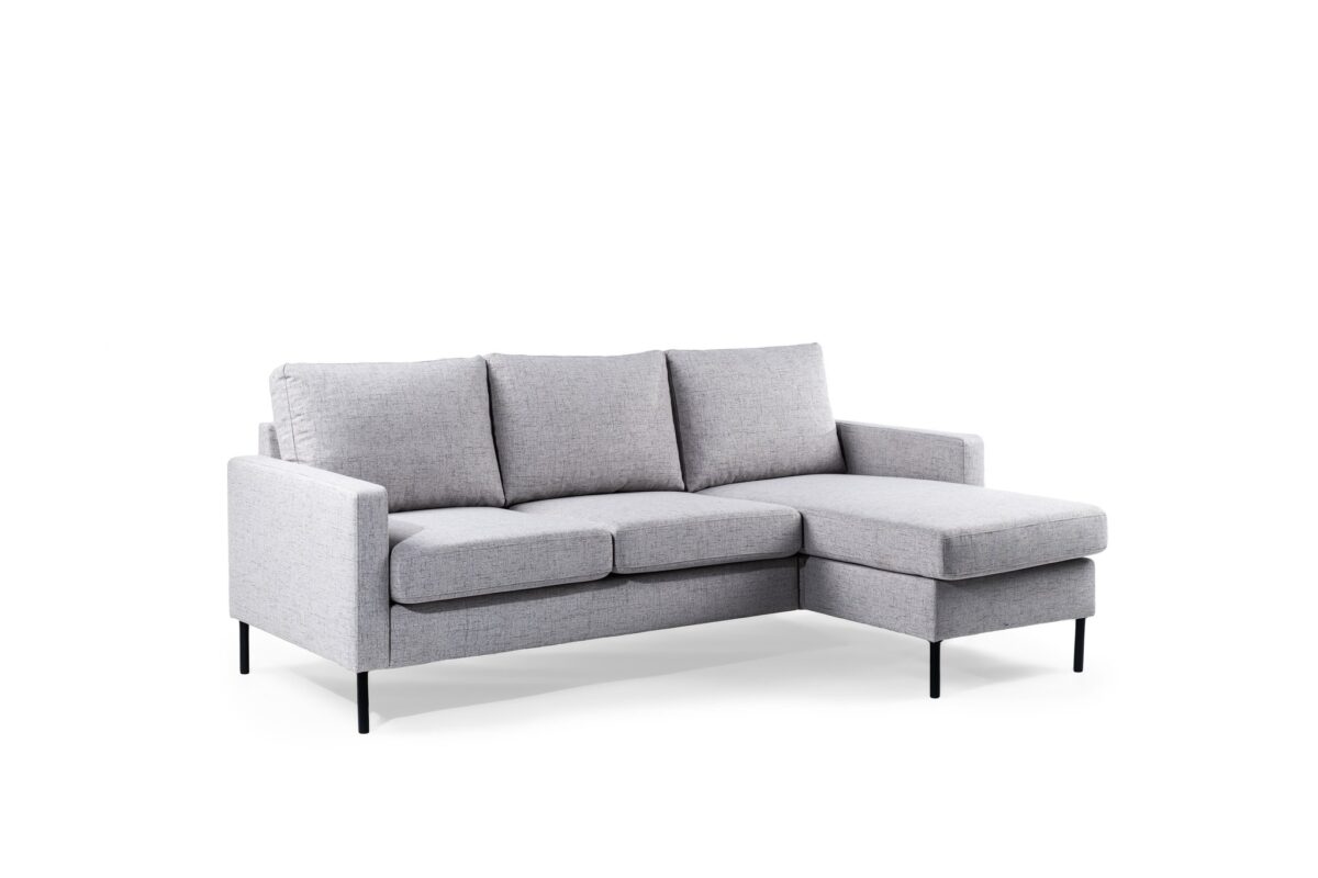 De 3 zits bank CL L+R in Valente V311 grijs stof is een moderne lichtgrijze sectionele bank met drie zitkussens, een chaise lounge aan de rechterkant en slanke zwarte metalen poten, getoond tegen een witte achtergrond.
