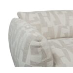 Close-up van een stoelhoek bekleed met structuurstof met een beige geometrisch patroon. De armleuning en rugleuning van de stoel zijn zichtbaar, wat de complexiteit van het ontwerp en de stiksels benadrukt.