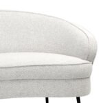 Moderne witte bank met een gebogen rugleuning en afgeronde randen, rustend op slanke zwarte poten. De stof oogt zacht en gestructureerd, wat een minimalistisch en elegant ontwerp creëert dat geschikt is voor hedendaagse interieurs.