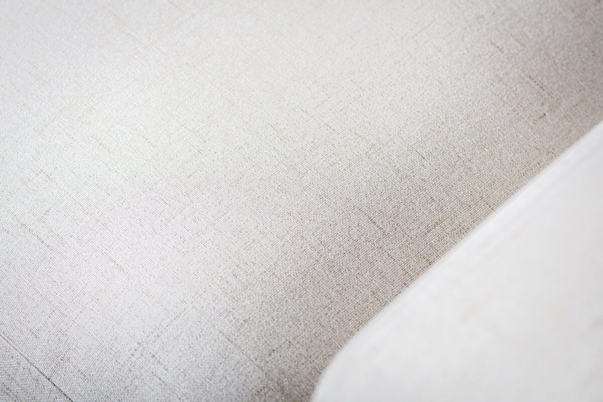 Close-up van de 3 zits bank CL L+R in de stof Valente V920 naturel, met de lichtbeige gestructureerde bekleding met subtiele geweven patronen en een licht gebogen rand aan de rechterkant.