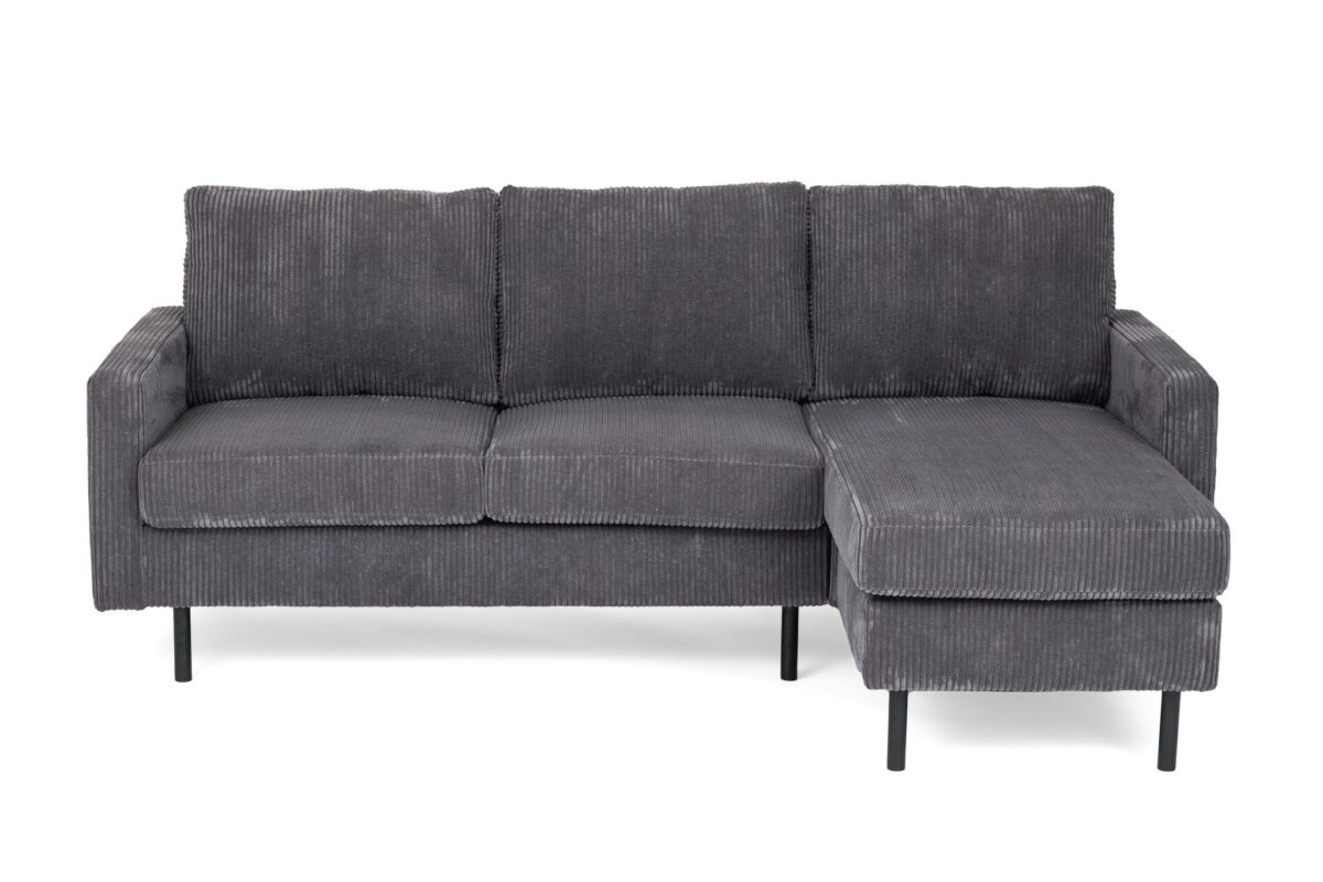 Grijze corduroy L-vormige sectionele bank met drie kussens en een chaise longue aan de rechterkant. Het heeft slanke zwarte metalen poten en een modern design. De bank staat tegen een witte achtergrond.