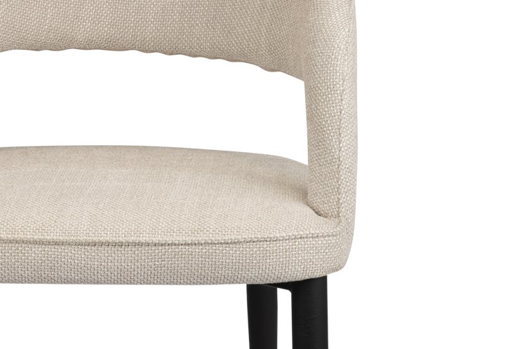 Close-up van een moderne stoel met beige structuurstof en een gebogen rugleuning. De stoel heeft zwarte poten, gedeeltelijk zichtbaar aan de onderkant. Het ontwerp is minimalistisch en eigentijds.