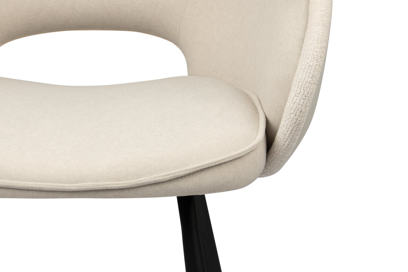 Close-up van een moderne beige stoel met een gebogen rugleuning en een gewatteerde zitting. De stoel heeft een strak en minimalistisch design, met donkere slanke poten. De bekleding lijkt zacht, wat de eigentijdse esthetiek versterkt.