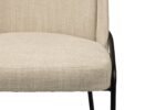Close-up van een beige stoel met textuurstof en een gewatteerde zitting en rugleuning. De stoel heeft een strak zwart metalen frame, zichtbaar aan de zijkanten en poten.