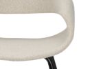 Close-up van een moderne, lichtbeige stoffen stoel met een gebogen rugleuning en een uitsparing. De stoel heeft een zwarte metalen poot die gedeeltelijk zichtbaar is. De algehele stijl is minimalistisch en eigentijds.