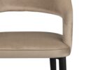 Beige gestoffeerde stoel met een gebogen rugleuning en zwarte poten, afgebeeld in close-up met de zitting en het onderste deel van de rugleuning. De stoel is geplaatst tegen een witte achtergrond.