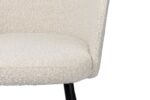 Close-up van een lichtbeige gestoffeerde stoel met een gebogen rugleuning en zwarte poten. De stof heeft een getextureerde, geweven uitstraling. De afbeelding richt zich op het onderste gedeelte van de stoel.