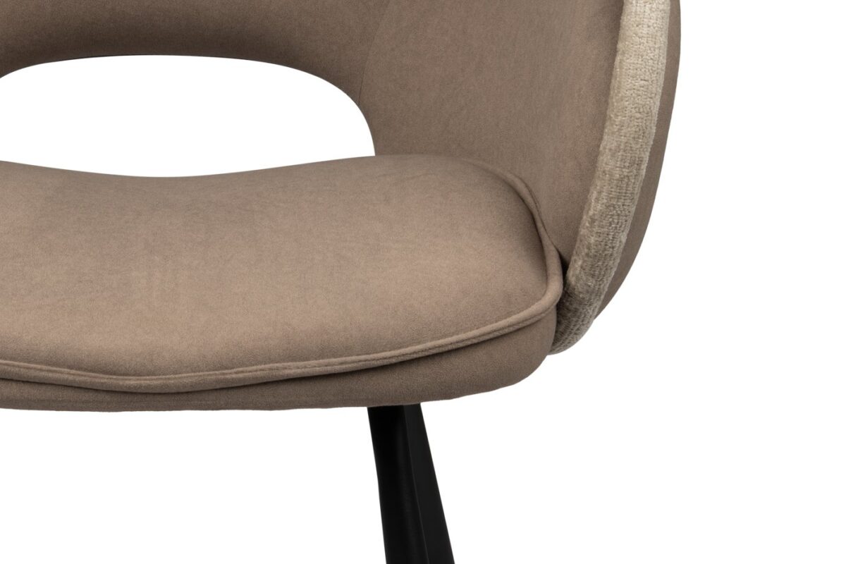 Close-up van een moderne stoel met een beige gewatteerde zitting en rugleuning, met een gebogen ontwerp en een zichtbare uitsparing aan de zijkant. De stoel heeft strakke zwarte poten, wat de eigentijdse stijl benadrukt.