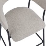 Close-up van een moderne stoel met een beige stoffen zitting en rugleuning. Het frame is strak en zwart, met een minimalistisch design. De gebogen arm en rugleuning van de stoel bieden een eigentijdse esthetiek.