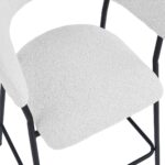 Een close-up van een stoel met een wit kussen met textuur en een zwart metalen frame. Het ontwerp heeft gebogen armleuningen en een eenvoudige, moderne esthetiek.