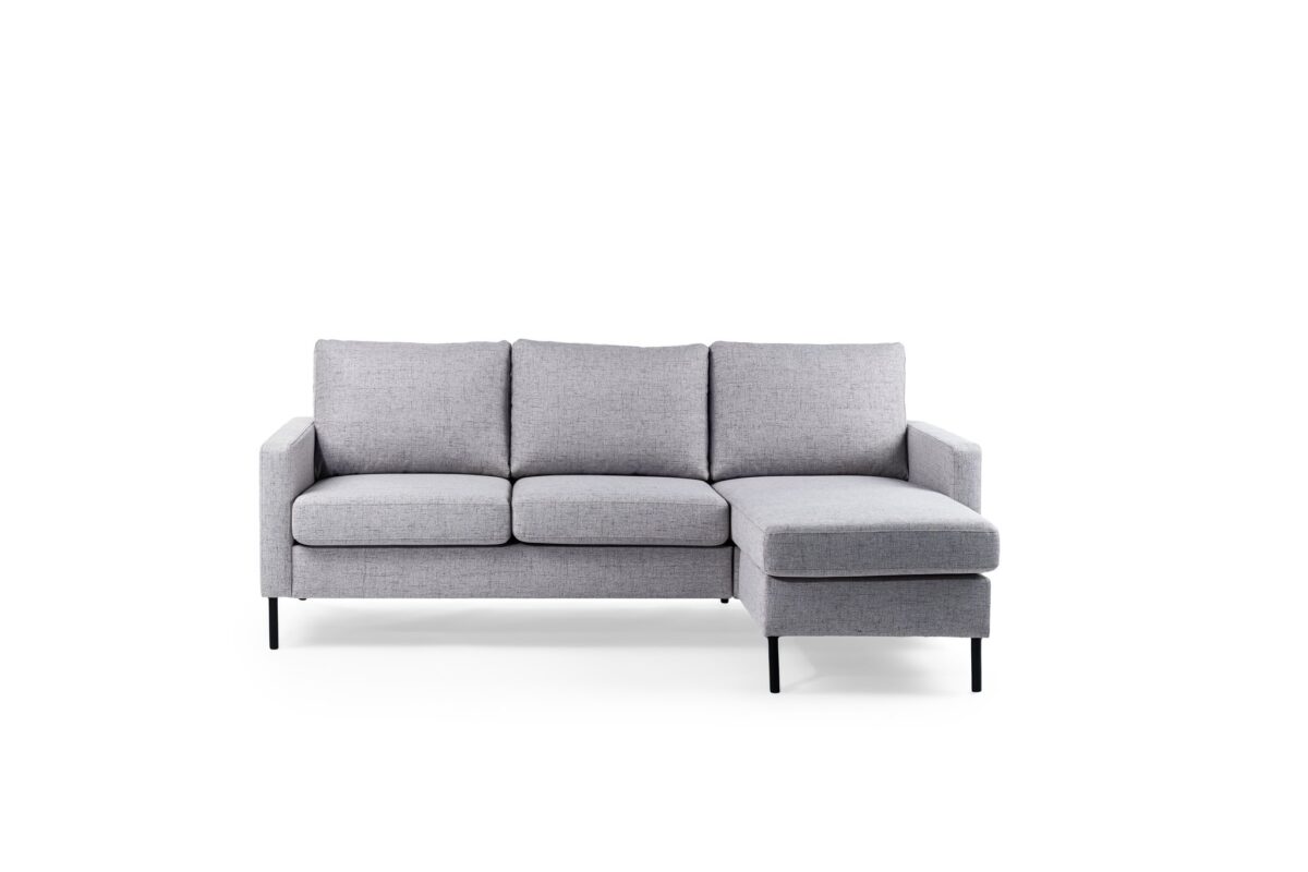 De 3 zits bank CL L+R, stof Valente V311 grijs is een lichtgrijze driezits sectionele bank met een chaise aan de rechterkant, slanke zwarte poten en een minimalistisch ontwerp, weergegeven tegen een effen witte achtergrond.