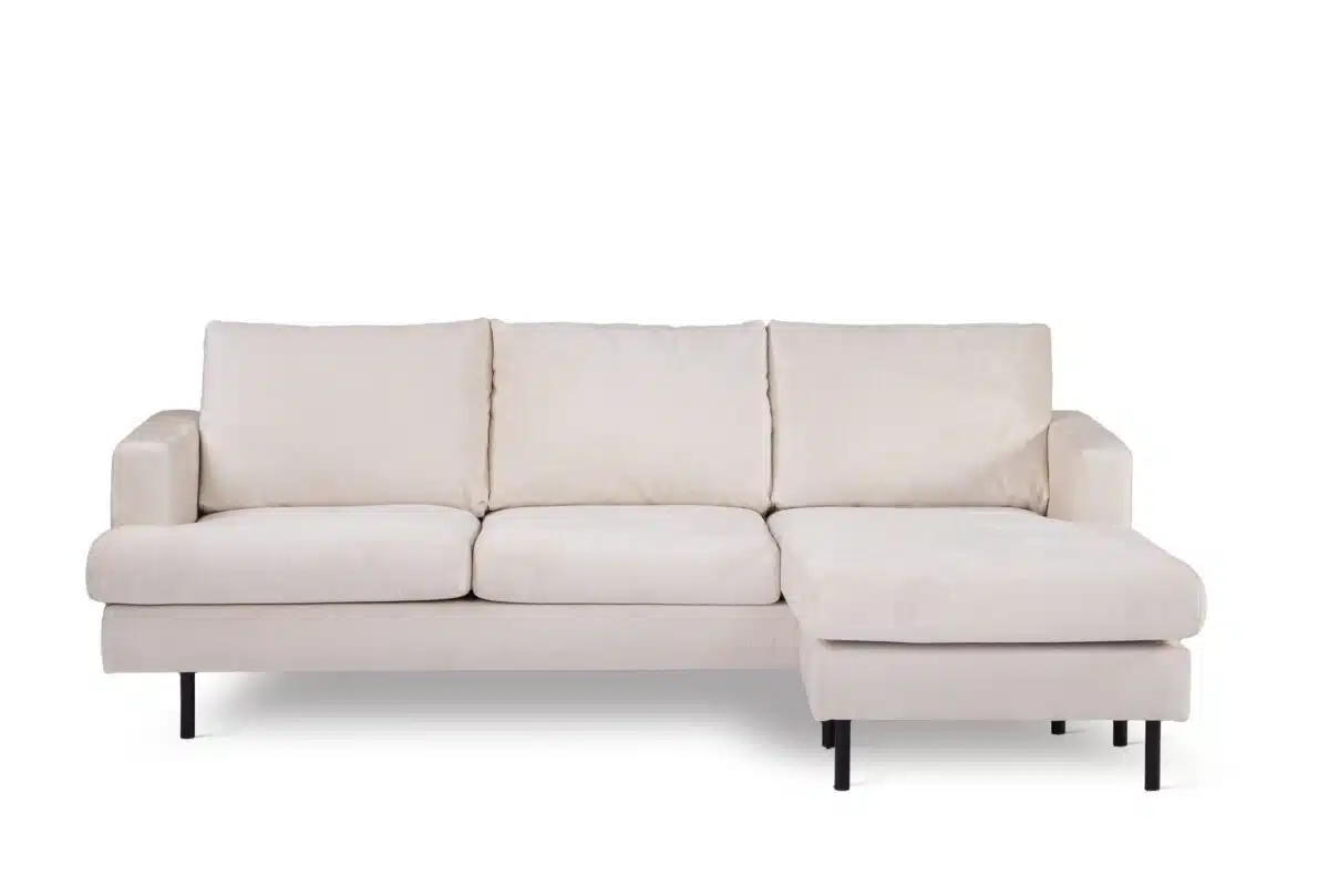 Een beige L-vormige sectionele bank met zachte kussens en zwarte poten, tegen een effen witte achtergrond. Het ontwerp heeft een chaise longue aan de rechterkant.