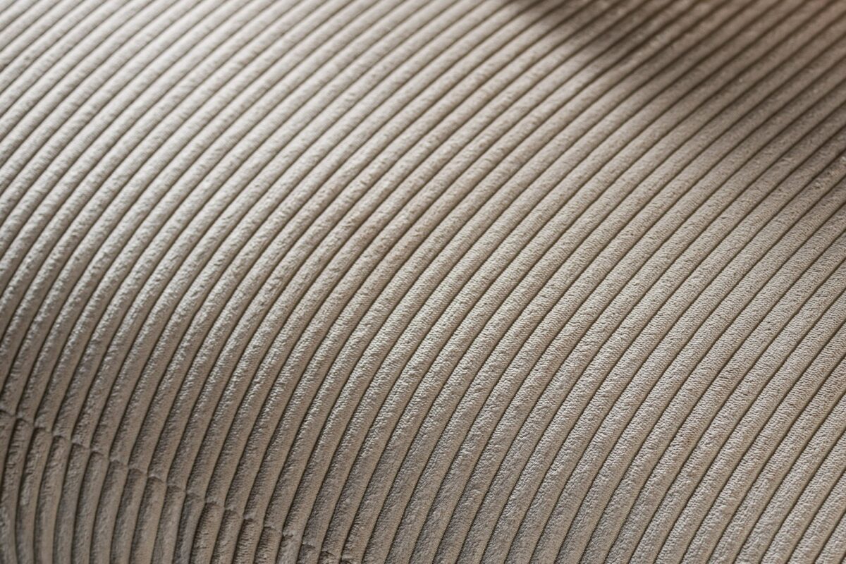 Close-up van de 3 zits bank CL L+R in stof Lincoln 83, RIB920 naturel, met beige corduroy stof met zachte verticale ribbels, gebogen oppervlak en gedetailleerde stiksels.