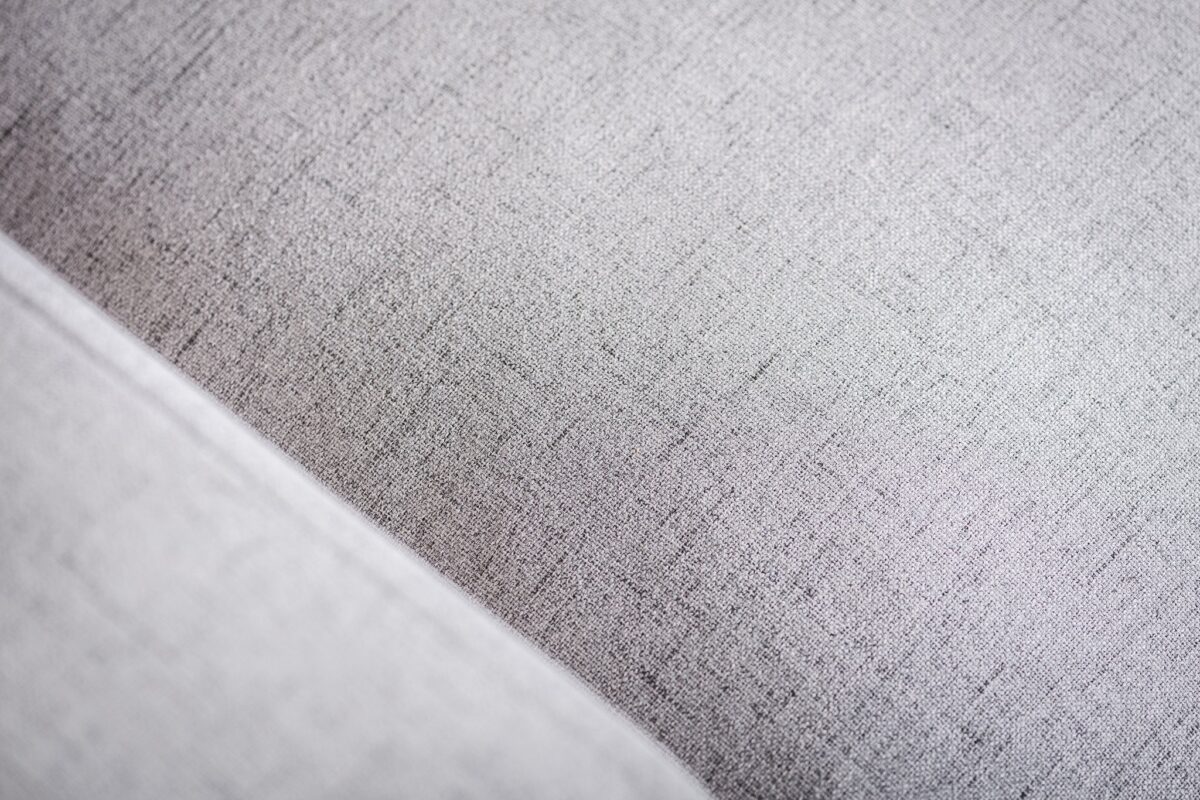 Close-up van de 3 zits bank CL L+R in Valente V311 grijs stof, met lichtgrijze bekleding met een subtiele geweven textuur en een diagonale naad in de linkerbenedenhoek.