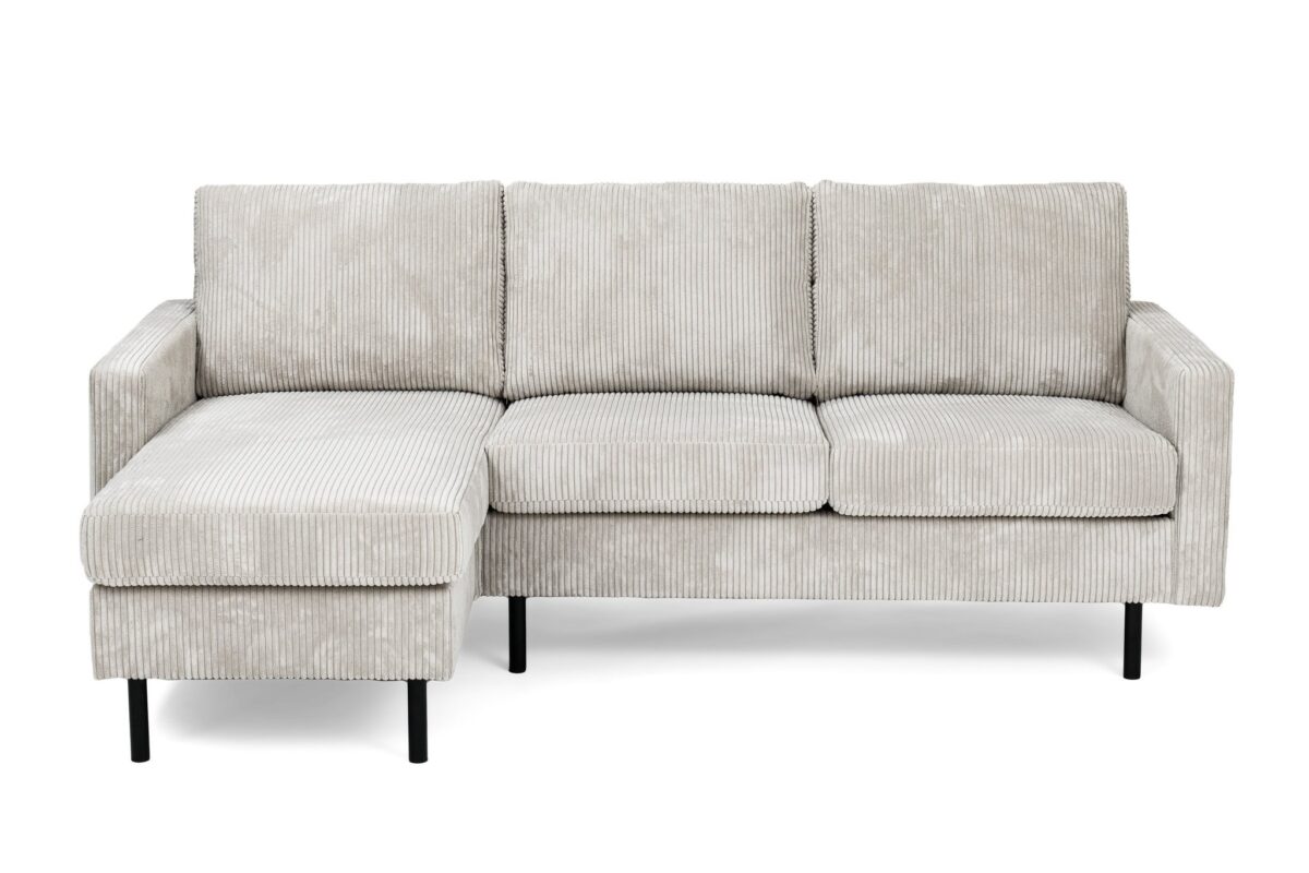 Een lichtgrijze, geribbelde stoffen sectionele bank met een L-vormig ontwerp. Het heeft drie zitkussens en een verlengde chaise longue aan de linkerkant. De bank heeft zwarte, slanke poten en een minimalistisch, modern ontwerp.
