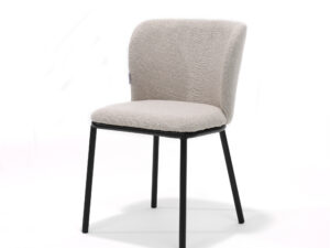 De Kim stoel Stof Teddy Natural is een moderne stoel met een lichtbeige zitting en rugleuning van teddystof, ondersteund door vier slanke, zwarte metalen poten, afgebeeld tegen een effen witte achtergrond.