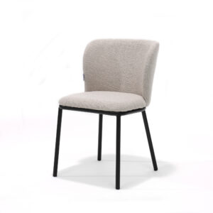 De Kim stoel Stof Teddy Natural is een moderne stoel met een lichtbeige zitting en rugleuning van teddystof, ondersteund door vier slanke, zwarte metalen poten, afgebeeld tegen een effen witte achtergrond.