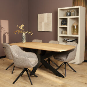 Moderne eetkamer met een houten tafel, zes Eetkamerstoel Jens | Bruine stoelen, een vaas met gedroogde bloemen en een lichte boekenkast met decoratie tegen een mauve muur en houten vloer.