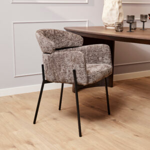 De Eetkamerstoel Otis | Grijs, met structuurgrijze bekleding en zwarte metalen poten, staat naast een donkere houten eettafel op een lichte houten vloer in een kamer met witte lambrisering en decoratieve accenten op de tafel.