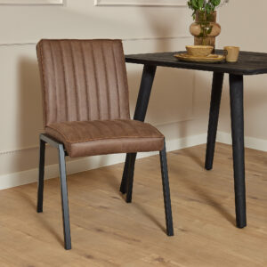 De Eetkamerstoel Tivoli | Bull Brown met zwarte metalen poten staat naast een zwarte houten tafel op een lichte houten vloer, omlijst door een beige lambrisering. De tafel is versierd met een vaas met bloemen en servies.