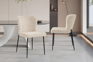 Twee Stoel 'Lisa' Bouclé Beige stoelen (set van 2) met zwarte metalen poten staan in een minimalistische eetkamer met een strakke tafel, neutrale muren en een eigentijds interieur.