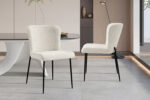 Twee Stoel 'Lisa' Bouclé Ecru stoelen (set van 2) met zwarte metalen poten staan in een moderne eetkamer met een grijze tafel, een minimalistische inrichting en neutrale kleuren.